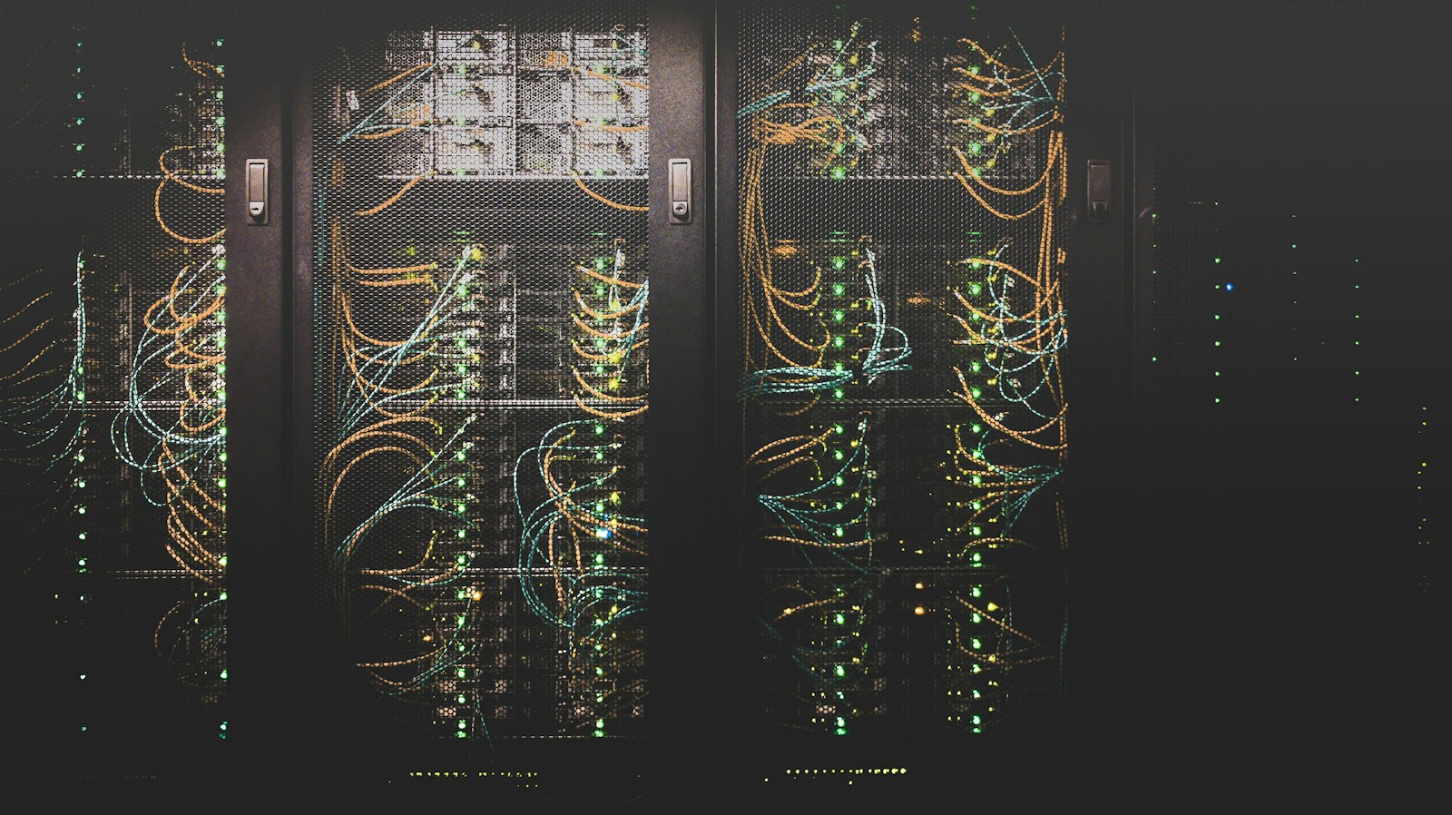 Dark server racks with dense network cabling and green status lights