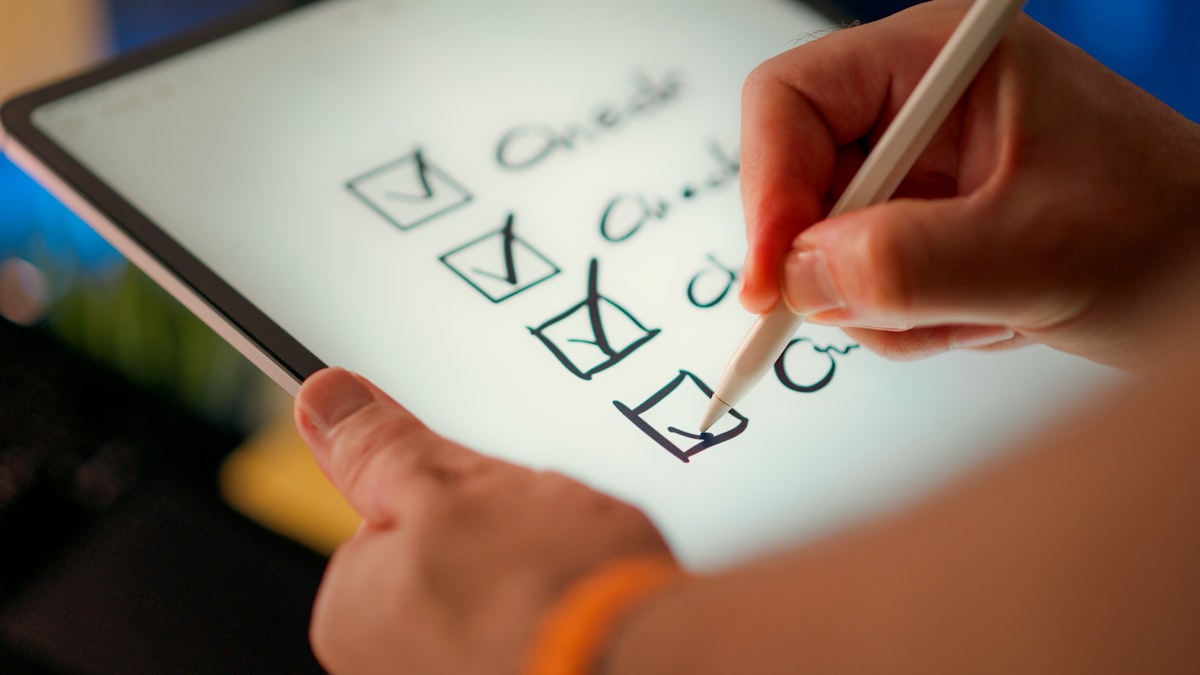 A hand checking off items on a checklist on a tablet