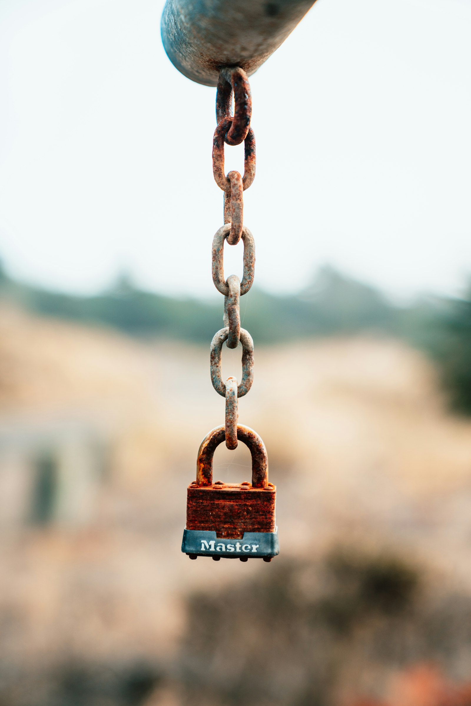 Rusted padlock hanging on a chain