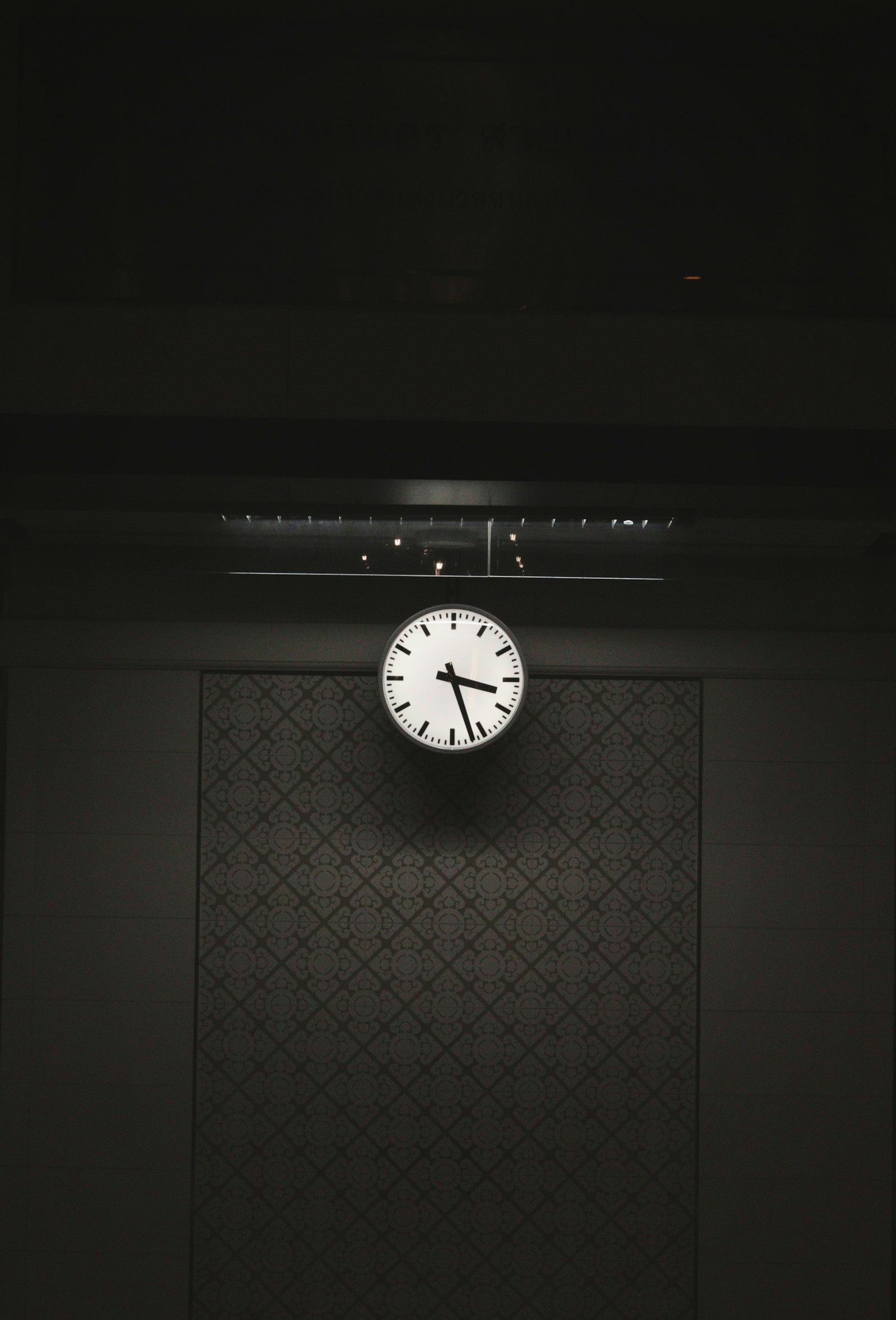 A clock on a wall in a dark, moody room