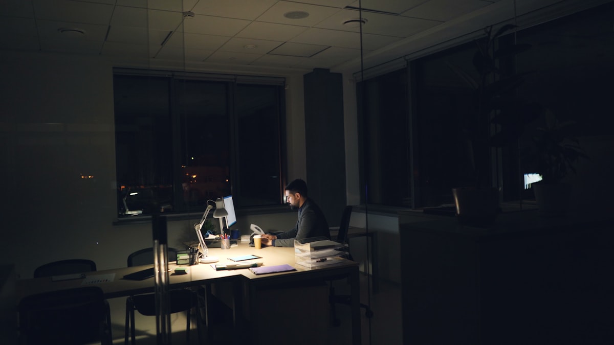 Man working alone at a desk in a dark office at night